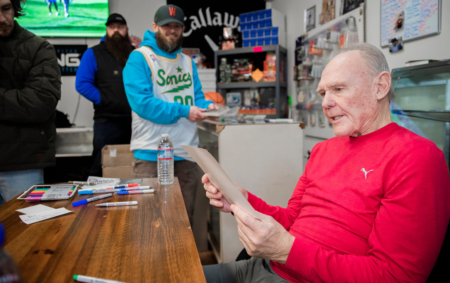 George Karl, who was inducted the Naismith Memorial Basketball Hall of Fame in 2022, looks over a poster while naming off players before signing an autograph on Friday at Keiper’s Cards in Centralia.